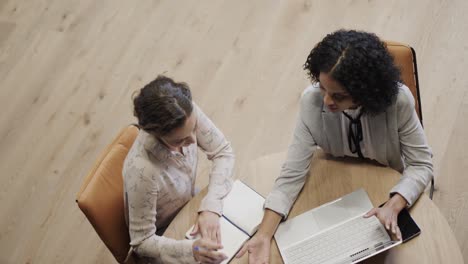 diversas compañeras en discusión usando computadora portátil en el salón de la oficina, cámara lenta