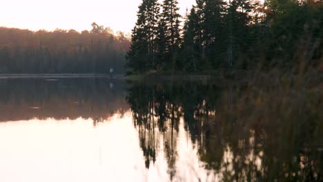 camper looking across a glassy lake at dusk