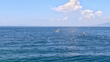 calm ocean waters with scattered buoys and a distant mountain under a clear blue sky.