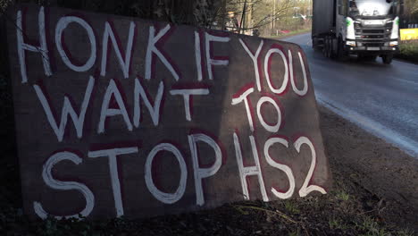 vehicles pass protest signs by the side of the road opposing the hs2 train line construction