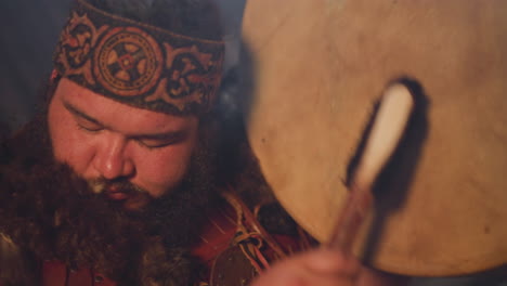 ecstatic obese man taps shamanic drum doing old ritual