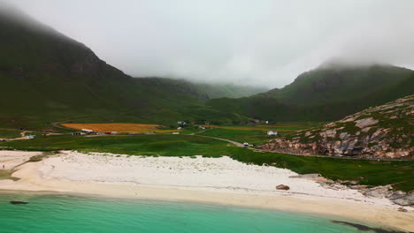 Impresionantes-Costas-De-Arena-Blanca-De-La-Playa-De-Haukland,-Lofoten,-Noruega,-Un-Exuberante-Valle-Y-Nubes-Detrás