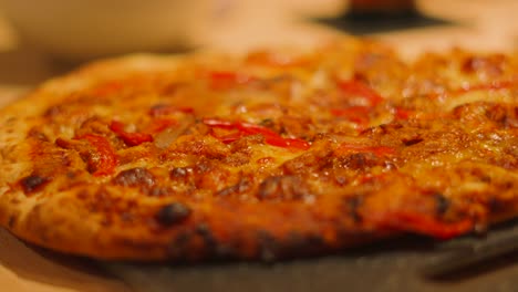 side view of bbq chicken pizza with peppers on table ready to be sliced into pieces and eaten by family or served to customers.