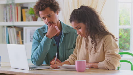 worried young couple in debt at home with laptop reviewing domestic finances together