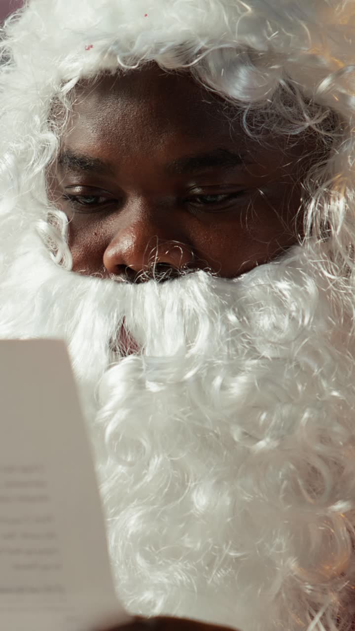 Babbo Natale afroamericano che legge una lettera di Natale e sorride.