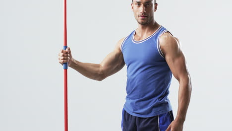 muscular athlete man holds a javelin at the gym on a white background