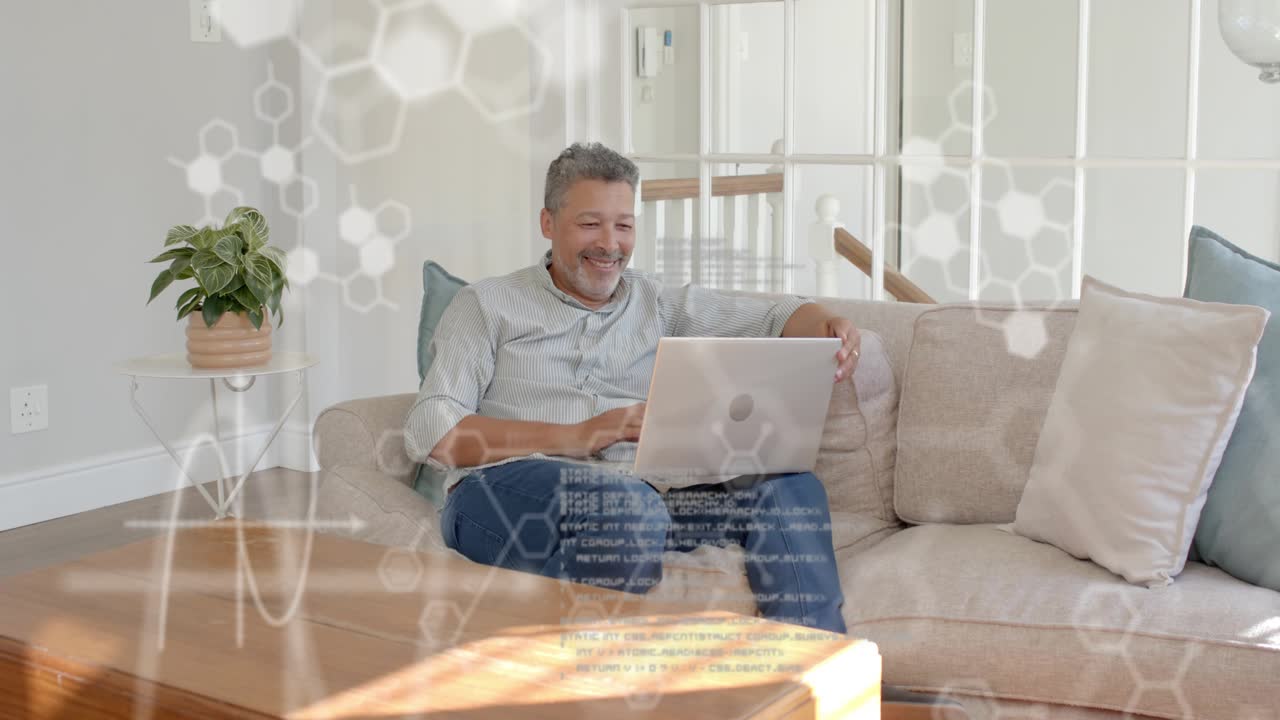 Mature man starting typing on laptop on sofa, reviewing code, hexagonal overlay eliciting gestures
