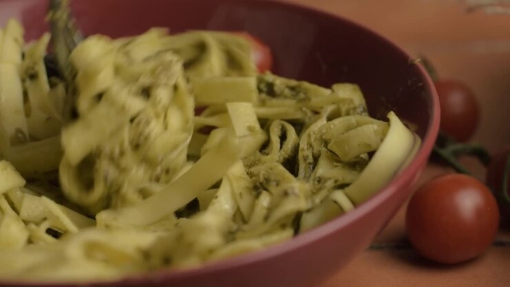 Primo piano di un piatto di tagliatelle al pesto con forchetta