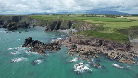 Tra-Na-Mbno-Beach-Copper-Coast-Waterford-Irland-Felsige-Küste-Bei-Ebbe-Mit-Der-Comeragh-Bergkette-Im-Hintergrund-Sommermorgen