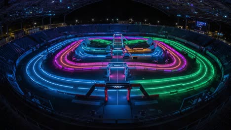 a stunning nighttime racing arena awash in colorful led lights showcasing a unique track layout designed for high-speed racing events and spectacle