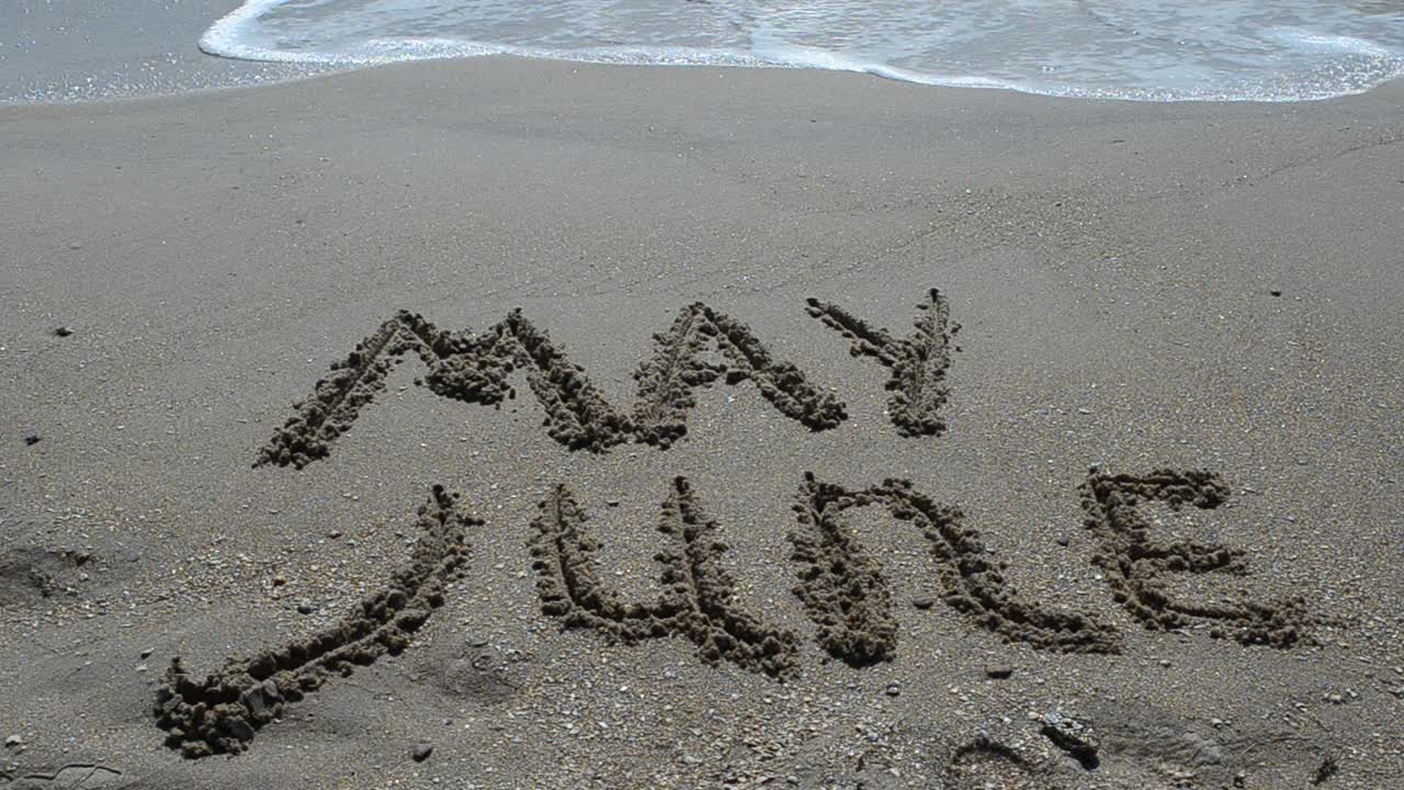 Inscription of the name of month on sand, the beach. Shooting on the beach