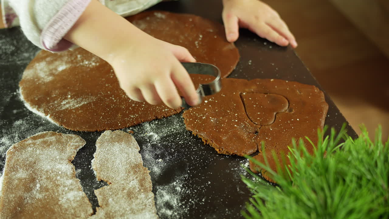 Close-up of little children's hands shaping hearts from gingerbread dough, Holiday baking traditions with kids in cozy kitchen, slow motion