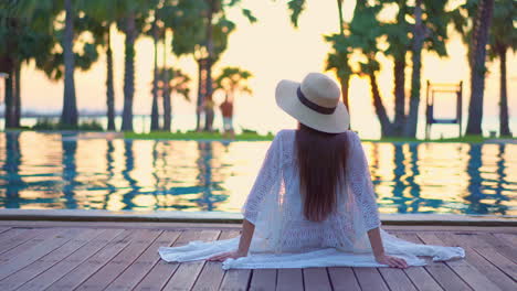 a woman relaxing by a swimming pool at a hotel near the beach at sunset