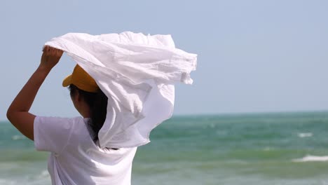 person unfurls a white towel by the seaside