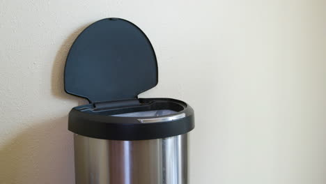 man throws away yellow package in motion sensing touchless trash can - medium side