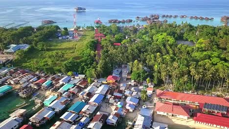 aerial flight over local village and clear ocean in malaysia, medium shot moving towards island in slow motion