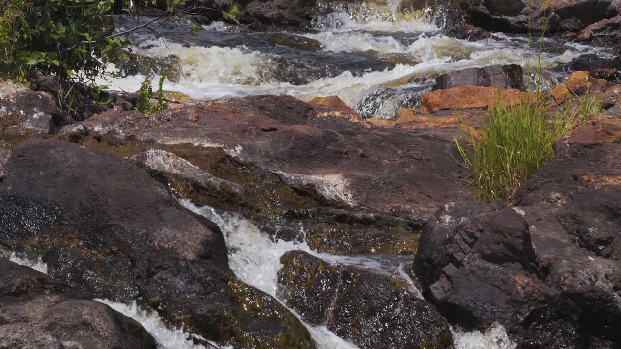Close-up of water flowing between rocks on the riverbank
