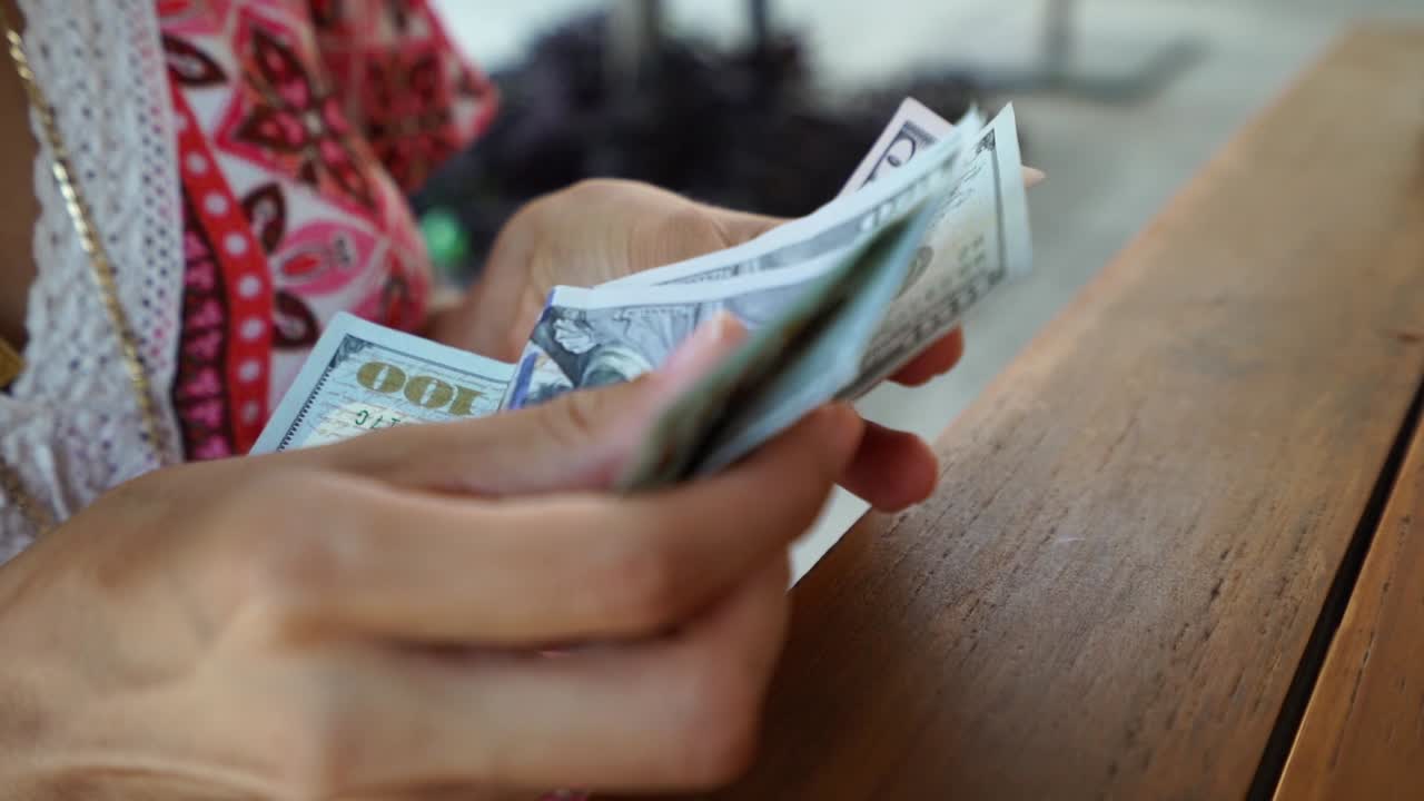 레스토랑 테이블에서 미국 100 달러 지폐와 50 달러 지폐를 계산하는 여성의 휴대용 측면 뷰