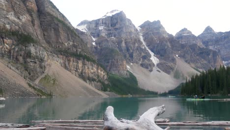 Landschaftsansicht-Am-Moränensee-Mit-Kanufahrern-Auf-Der-Oberfläche-Des-Grünen-Spiegelsees-Und-Den-Rockies-Bergen-Im-Sommer-Tagsüber