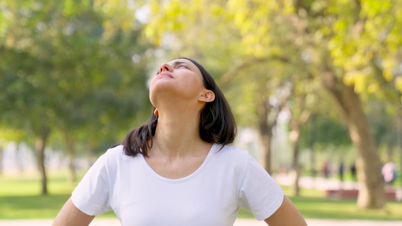 mujer india haciendo estiramiento de cuello en un parque por la mañana