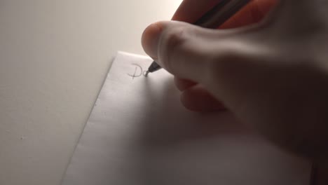 free handwriting on a blank white pad paper with a black ink pen - closeup shot