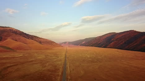 Aerial:-Straight-road-in-flat-pasture-valley-in-Canadian-mountains