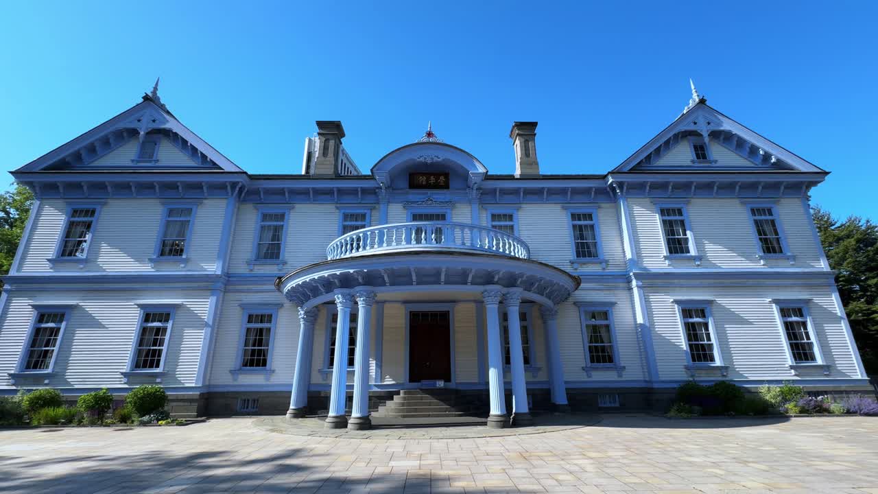 A beautiful historic building with blue trim, featuring a rounded porch and stairs