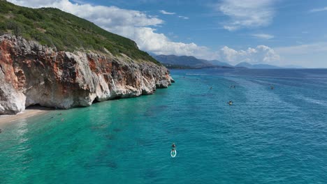 crystal-clear water at gjipe beach in albania, with paddleboarders enjoying the day