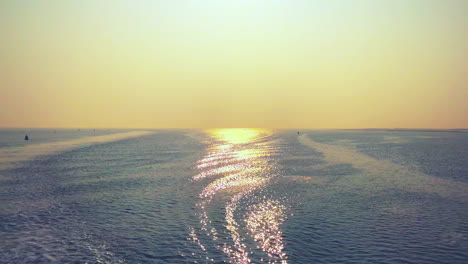 landscape wide shot of a surrealist sunset over sea horizon with light reflections in the water