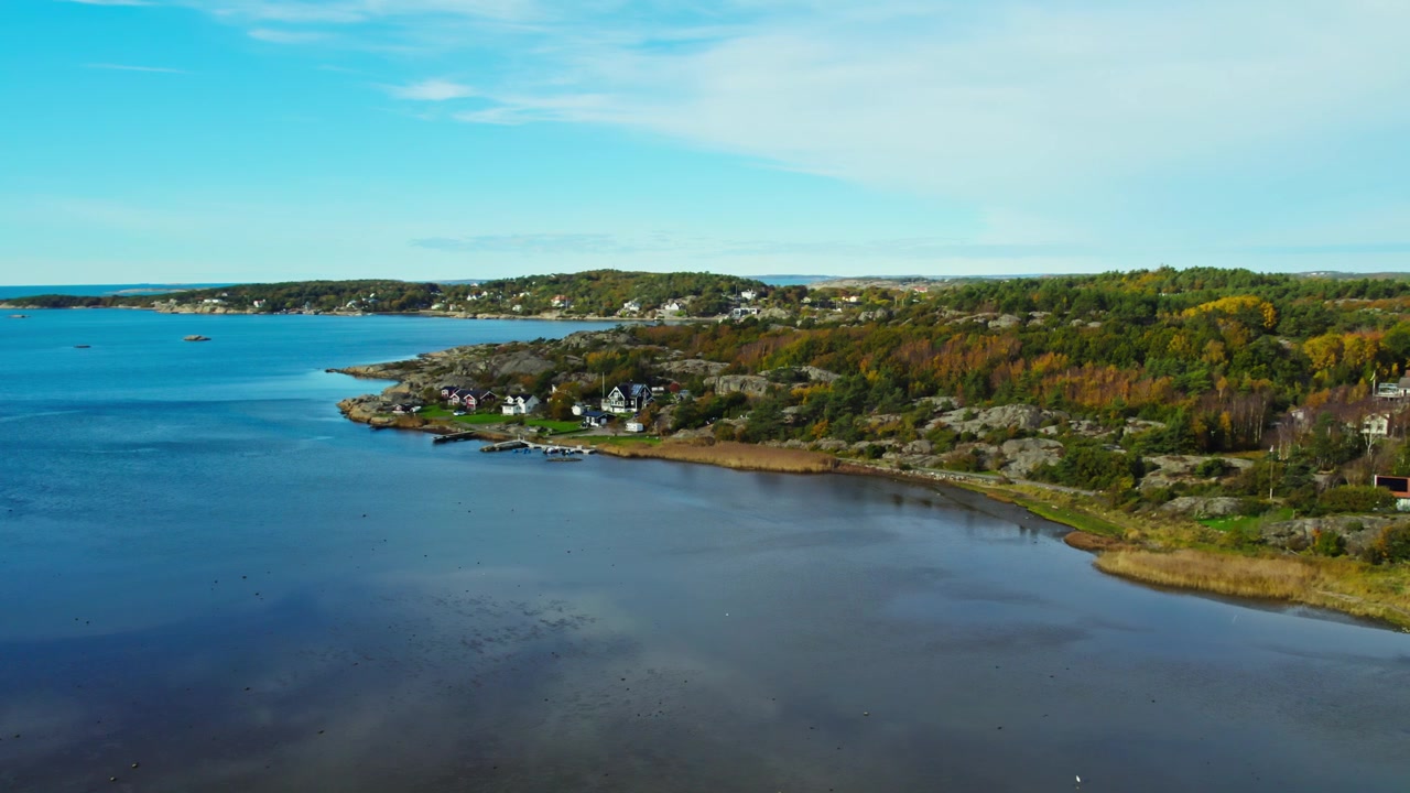 Dronekuva rauhallisesta rannikosta, sinisestä lahdista, metsästä ja rannikon kodeista Länsirannikolla kirkkaan taivaan alla lähellä Kungsbackaa, Hallandissa, Ruotsissa.
