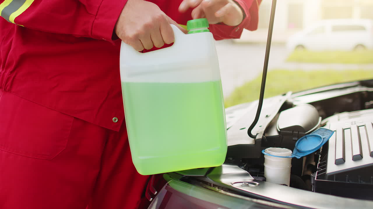 서비스 직원 남자는 자동차 앞유리 녹색 청소 세탁기 유리 여름 또는 겨울 청소기를 붓습니다