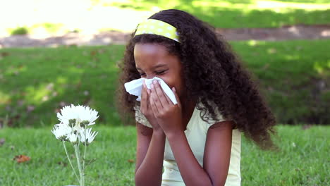 una niña estornudando de fiebre del heno en el parque