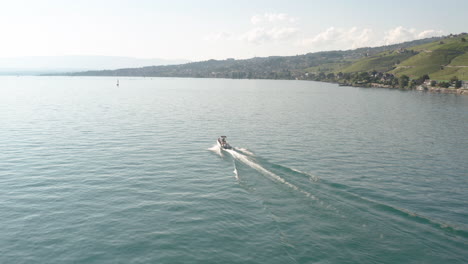 flying towards fast speedboat driving over a beautiful, blue lake