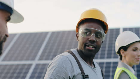 close-up view of three multiethnics farm solar engineers talking and walking in solar plantation