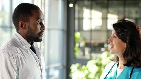 mixed-race male and female doctors talking cheerfully in clinic