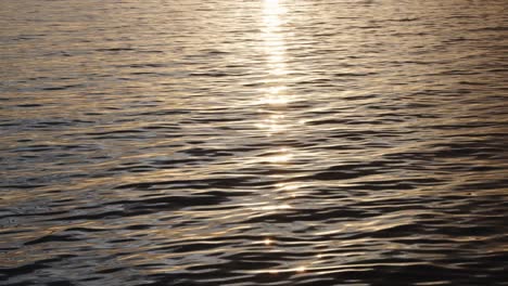 Nahaufnahme-Des-Plätschernden-Wassers,-Während-Die-Kamera-Nach-Oben-In-Richtung-Sonne-Und-Inselsilhouette-Schwenkt