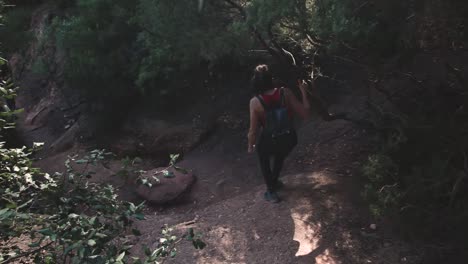 Young-travelling-woman-walking-on-steep-rocky-path-during-trekking-in-woodland