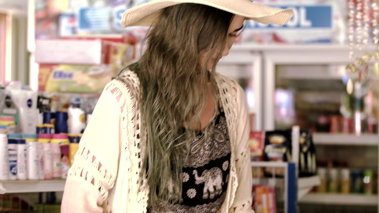 모자를 입은 소녀는 식료품 가게에서 현금으로 지불합니다.