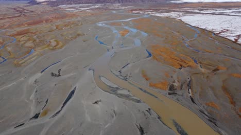 Arroyo-Del-Río-En-Llanuras-Marrones-Fangosas-Con-Limo-Y-Nieve-Glacial,-Islandia