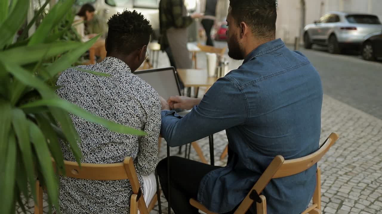 freelancers usando computadora portátil y hablando en un café al aire libre