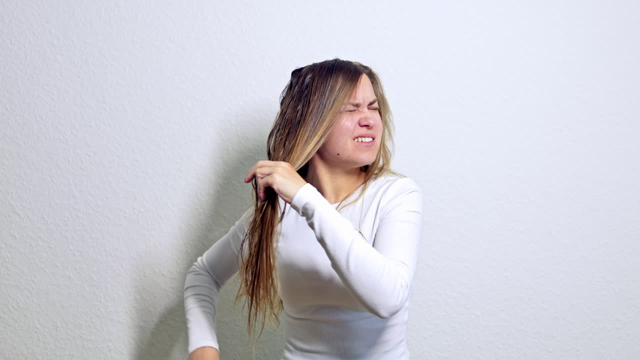 Jovem mulher bonita penteando o cabelo comprido. Mulher penteando o cabelo molhado com uma escova. Cabelo feminino comprido, limpo e lavado