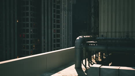 urban rooftop perspective featuring pipes and city buildings at night