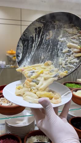 4k shot of creamy white sauce pasta being served from skillet to plate. hot, steamy, and deliciously textured. ideal for food ads, cooking channels, and recipe visuals. rich detail and color.