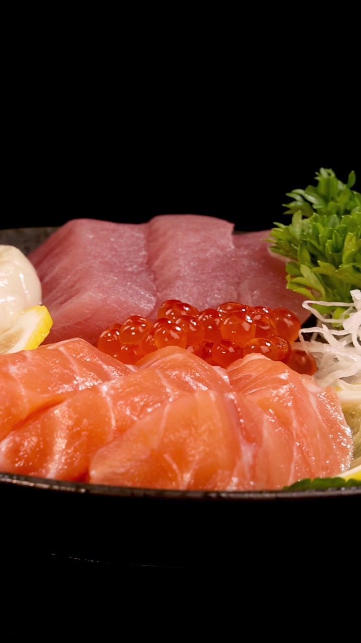Un vivace piatto di sashimi con salmone, tonno, capasanta, uova di salmone e guarnizioni ruota fluidamente sotto una luminosa illuminazione da studio su sfondo nero