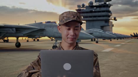 military personnel working on laptop on aircraft carrier deck