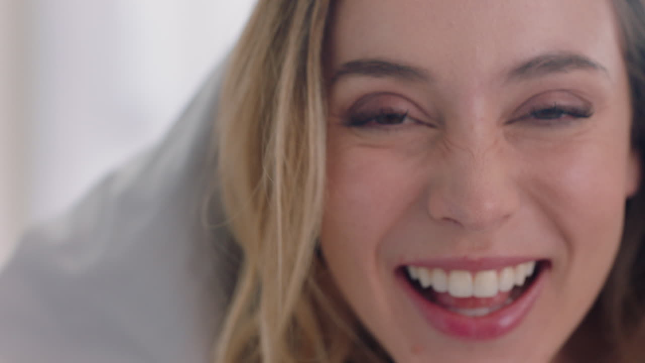 hermosa mujer jugando en la cama escondiéndose bajo una manta divirtiéndose disfrutando de una mañana lúdica en casa