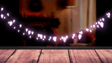 Glowing-pink-fairy-light-decoration-hanging-over-textured-wooden-plank