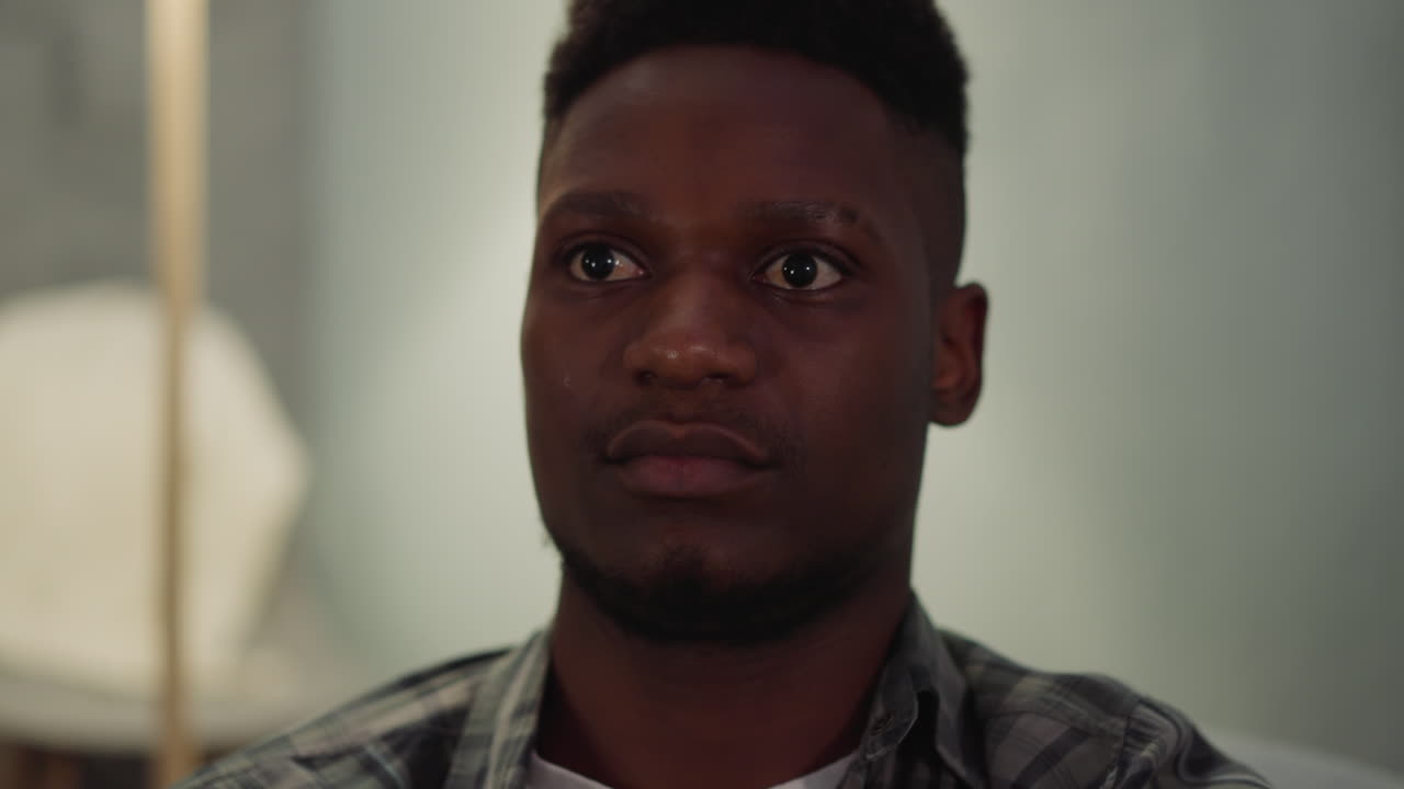 Giovane uomo afroamericano tranquillo è seduto nel soggiorno