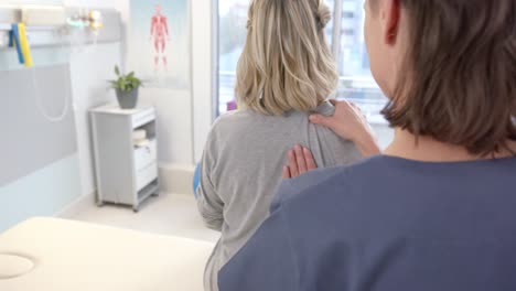 fisioterapeuta caucásica masajeando la espalda de una paciente anciana en un centro de rehabilitación