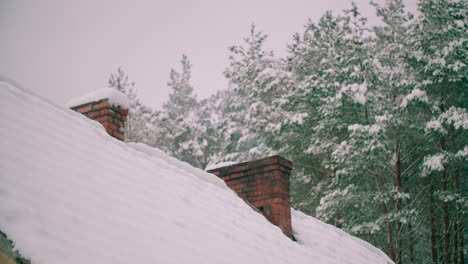 A-red-brick-chimney-on-the-roof-of-a-house-covered-with-fresh-snow